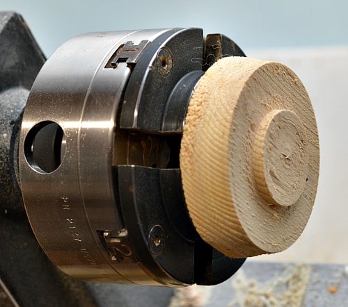 Attache a scrap piece of wood to the lathe to make a jam chuck for the tea light.